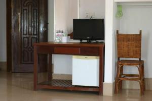 escritorio de madera con TV y silla en Angkor Ruby Guesthouse, en Siem Reap