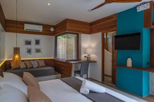 a bedroom with a bed and a couch and a tv at Bird of Paradise in Panglao