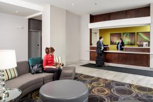 a woman sitting on a couch in a hotel lobby at Candlewood Suites West Edmonton - Mall Area, an IHG Hotel in Edmonton