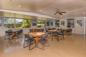 a dining room with tables and chairs and windows at Riverside Lodge Paihia in Paihia
