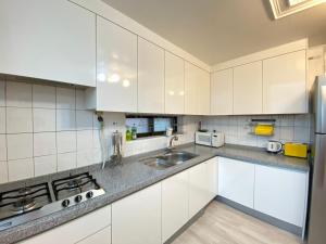 a kitchen with white cabinets and a sink at Kang's Apartments in Central Seoul in Seoul