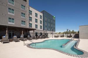 a pool in front of a building with chairs and tables at Holiday Inn Express & Suites - Odessa I-20, an IHG Hotel in Odessa