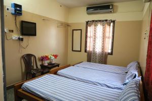 a bedroom with two beds and a window at R. VE. R Residency in Thanjāvūr