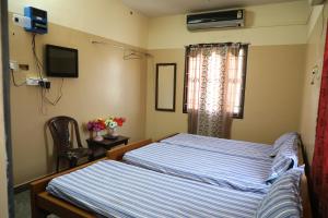 1 Schlafzimmer mit 2 Betten und einem Fenster in der Unterkunft R. VE. R Residency in Thanjavur