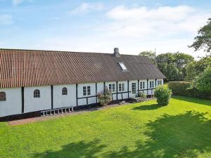 une maison blanche avec un toit rouge et une cour dans l'établissement Holiday home Aakirkeby IX, à Åkirkeby