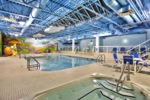 una gran piscina cubierta con sillas y una bañera de hidromasaje. en Holiday Inn Express Winnipeg Airport - Polo Park, an IHG Hotel en Winnipeg