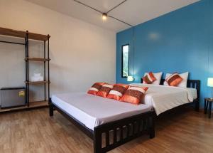 a bedroom with a large bed with a blue wall at Koh Kood Chalet in Ban Hin Dam