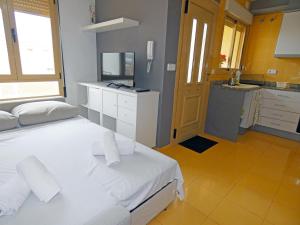 a bedroom with a white bed and a kitchen at Anacasa Avinyo Sector 5 AP121 in Oliva