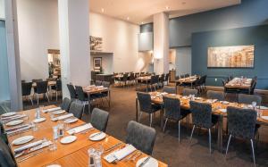 un ristorante con tavoli lunghi e sedie in una stanza di Scenic Hotel Dunedin City a Dunedin