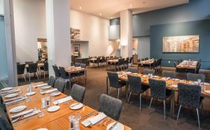 a restaurant with long tables and chairs in a room at Scenic Hotel Dunedin City in Dunedin