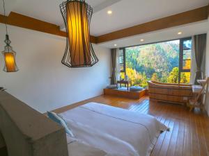 una camera con un grande letto e una grande finestra di Mount View Cottage a Zhangjiajie