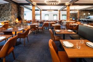 a restaurant with wooden tables and chairs and a fireplace at Peppers Cradle Mountain Lodge in Cradle Mountain