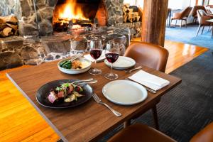 a table with a plate of food and glasses of wine at Peppers Cradle Mountain Lodge in Cradle Mountain