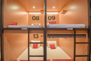 two bunk beds in a small room with red pillows at Tokyo Cubo in Bandung