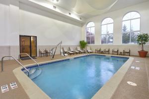 uma grande piscina numa grande sala com mesas e cadeiras em Holiday Inn Express & Suites Chicago-Libertyville, an IHG Hotel em Libertyville