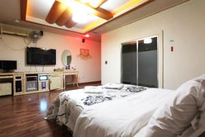 a bedroom with a white bed and a flat screen tv at Motel Nine in Daejeon