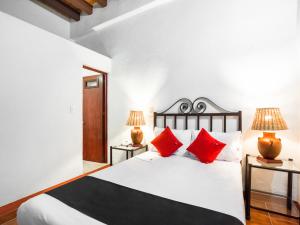a bedroom with a white bed with red pillows at Hotel El Nito Posada in Oaxaca City