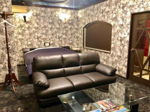 a living room with a leather couch and a bed at Hotel Mermaid (Leisure Hotel) in Beppu