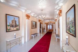 a hallway with a red carpet and paintings on the walls at Hotel Royal Craiova in Craiova