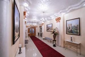 a hallway with a red carpet and paintings on the walls at Hotel Royal Craiova in Craiova