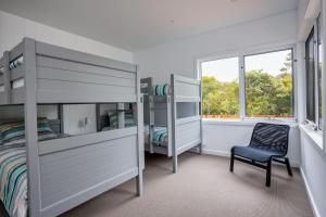 1 dormitorio con literas, silla y ventana en Molly's Beach House:, en Blairgowrie