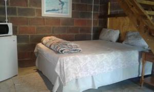 a bed in a room with a brick wall at Lothian rd Cottage in Durban
