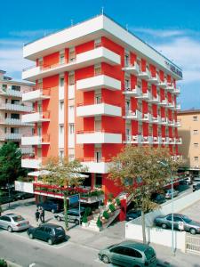 czerwony budynek z samochodami zaparkowanymi na parkingu w obiekcie Hotel Nelson w mieście Lido di Jesolo