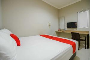 een slaapkamer met een bed, een bureau en een televisie bij RedDoorz @ Mangga Besar 2 in Jakarta