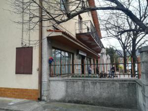 a building with a balcony and a person sitting on the porch at Coretti Rooms in Trieste