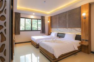 a hotel room with two beds and a window at The Mantra Hotel Kata Noi in Kata Beach