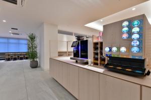 a lobby with a counter with a tv and a bar at REF Kumamoto by VESSEL HOTELS in Kumamoto