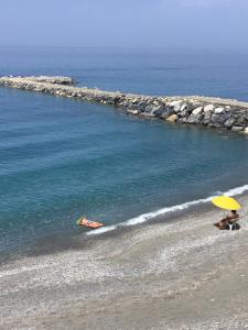 a couple of people sitting on a beach with an umbrella at Villa la Ficuzza in Cittadella del Capo