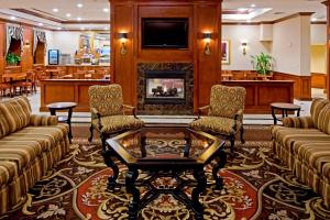 a lobby with a fireplace and couches and a table at Rockville Centre Hotel - JFK Airport in Lynbrook