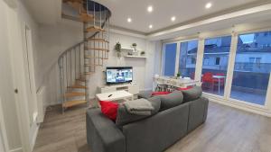 a living room with a gray couch and a television at Fantástico apartamento, cerca de todo, para disfrutar de la ciudad in A Coruña