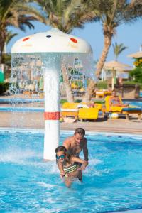 a man in a swimming pool jumping in the water at The Three Corners Sunny Beach Resort in Hurghada
