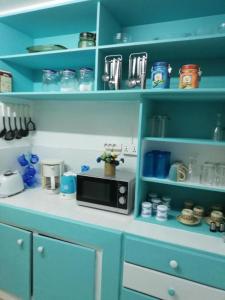 a kitchen with blue shelves and a microwave on a counter at Casa Marina- Flic en Flac - Beach is right in front of the Villa-Just cross the road in Flic-en-Flac