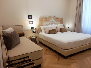 a bedroom with two beds and a chair at Casa Vittoria Napoli - Santa Lucia in Naples