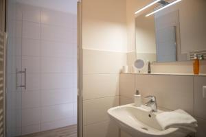 
a white sink sitting under a mirror in a bathroom at Hotel Hanseat Stralsund in Stralsund
