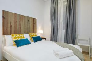1 dormitorio con 1 cama blanca grande con almohadas azules y amarillas en LEEWAYS APARTMENT in GRAN VÍA XIV en Madrid
