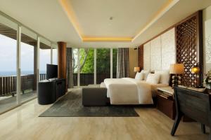 a bedroom with a bed and a desk and a television at Anantara Uluwatu Bali Resort in Uluwatu