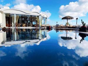 un edificio con reflejo en una piscina de agua en Villa Manos Hotel en Karterados