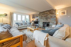a living room with couches and a stone fireplace at Palm Trees in Polzeath