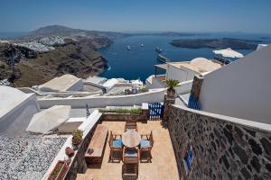 a balcony with tables and chairs and a view of the water at Santorini Folia Bianca in Imerovigli