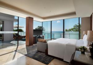 a bedroom with a bed and a view of the ocean at Anantara Uluwatu Bali Resort in Uluwatu