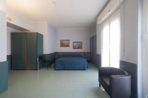 a bedroom with a bed and a chair and a window at Hotel Tirreno in Genoa