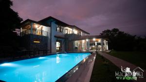 a villa with a swimming pool at night at Machan Villa in Tangalle