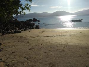 een strand met een boot in het water bij Ubatuba Surf Hostel, apenas a 60 metros da praia da Lagoinha! in Ubatuba