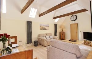 ein Wohnzimmer mit einem Sofa und einer Uhr an der Wand in der Unterkunft Heron's Hideaway in Wells next the Sea