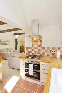 a kitchen with a stove and a living room at Heron's Hideaway in Wells next the Sea