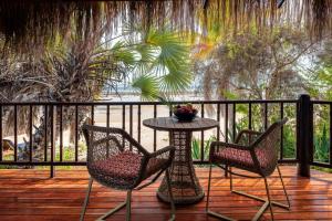 dwa krzesła i stół na drewnianym tarasie w obiekcie Anantara Bazaruto Island Resort w mieście Bazaruto